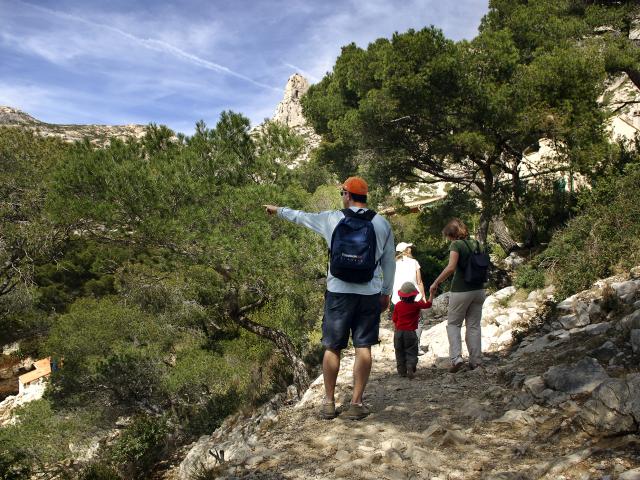 Promeneurs en famille sur le sentier des Calanques, entourés de pins