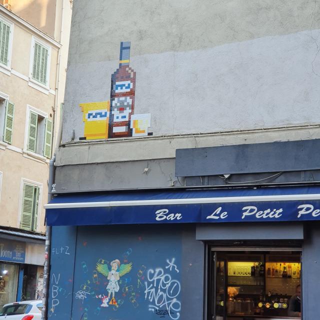 Rue du cours Julien avec oeuvre street art space invader d'un verre et d'une bouteille de pastis