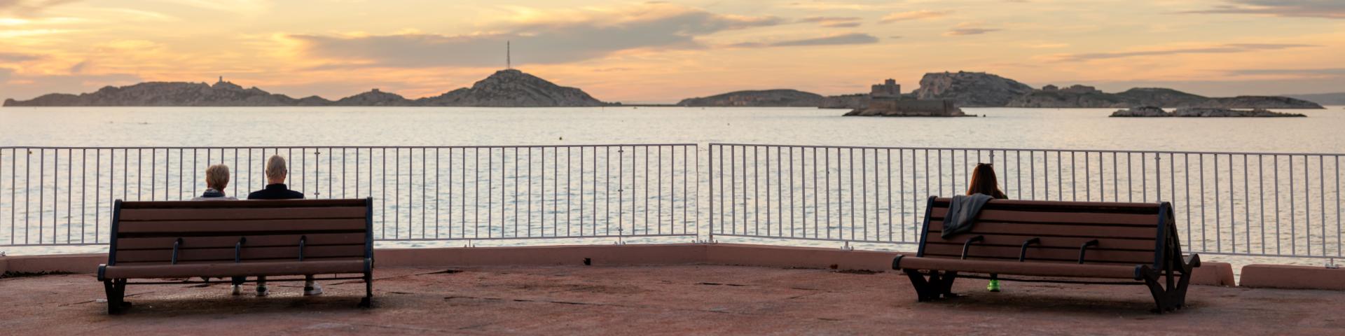 Personne sur un banc admirant le coucher de soleil sur la Corniche Kennedy à Marseille