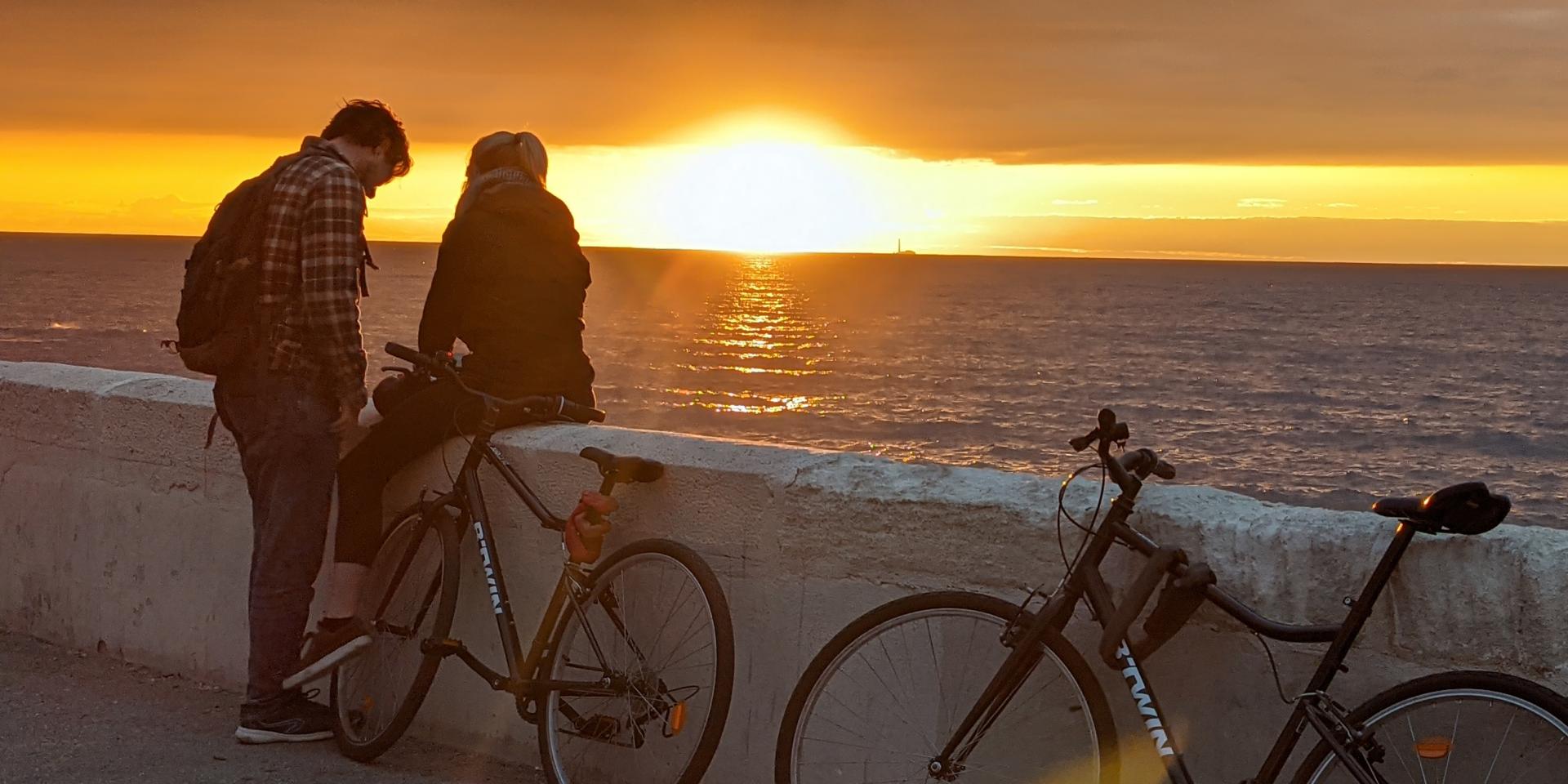 Couple avec des vélos admirant le coucher de soleil sur la Corniche Kennedy