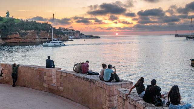 personne assise sur muret qui regardent le coucher de soleil depuis le Fort St jean