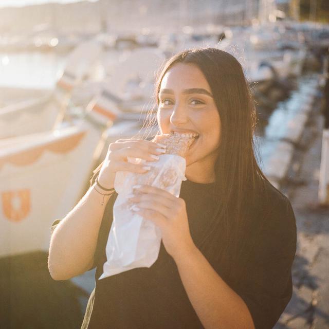 femme mangeant un chichi freggi sur le port de l'Estaque à Marseille