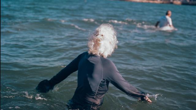 Personne aux cheveux blancs dans la mer pratiquant le longe-côte.