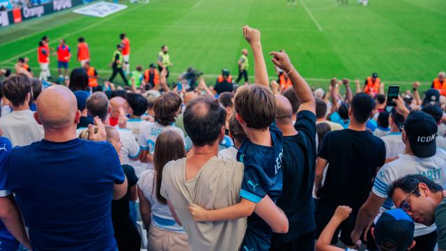 Homme supporters de foot tenant son fils dans les bras, dans le stade Orange Vélodrome