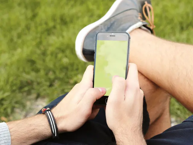 Personne jouant à Pokémon GO sur son smartphone en extérieur.